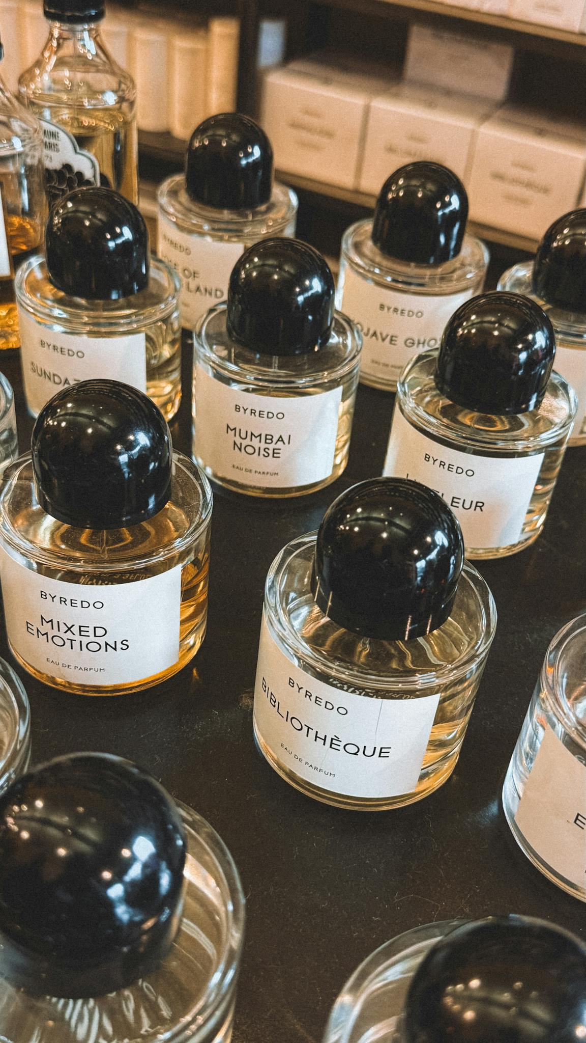Close-up view of various Byredo perfumes with elegant labels arranged on a shelf.