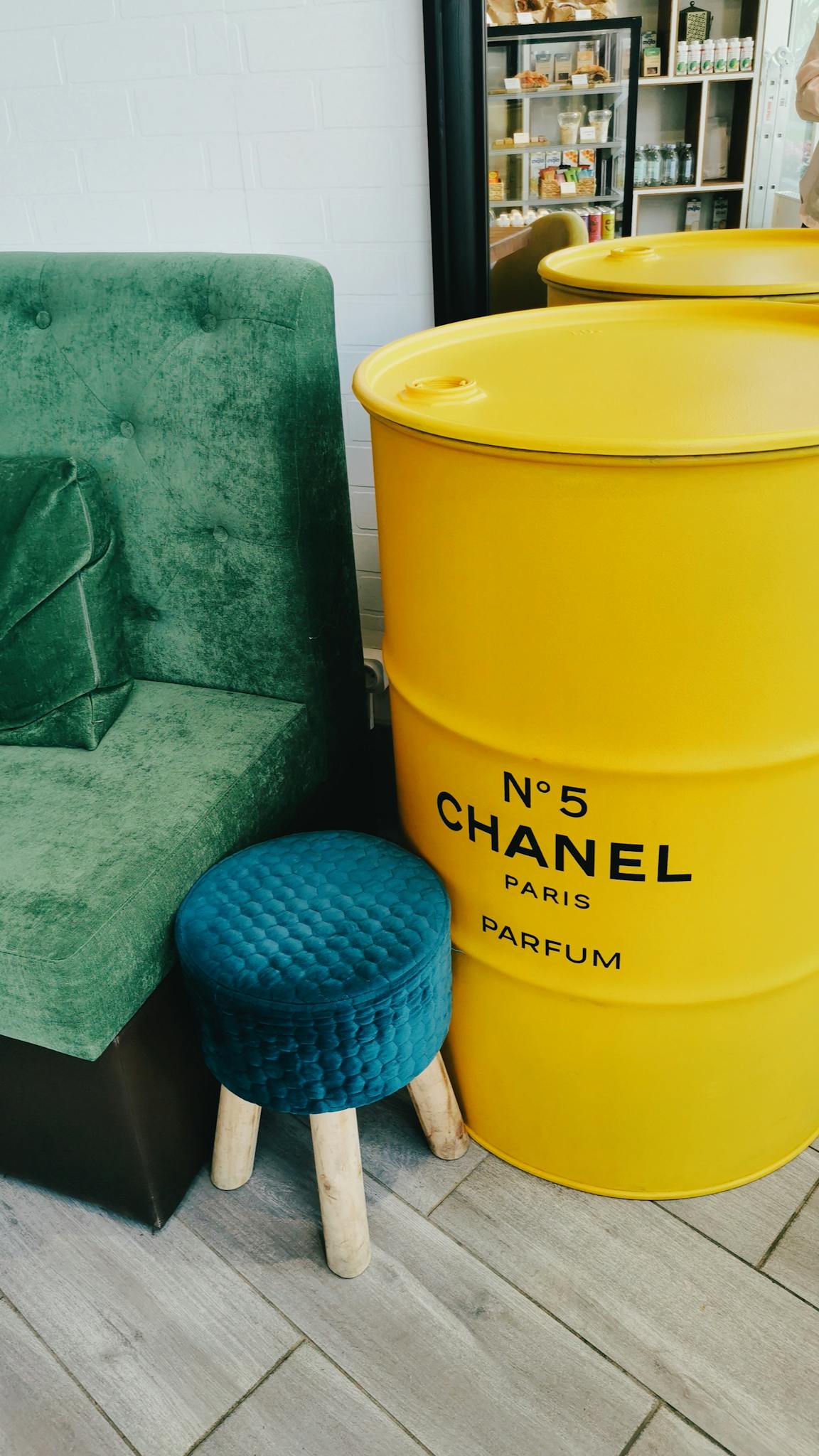 Stylish setup featuring a Chanel barrel, velvet sofa, and tufted stool for a chic interior look.